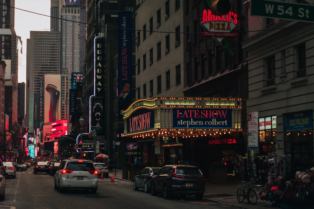 bustling city street at night with neon signs for a theater and restaurants