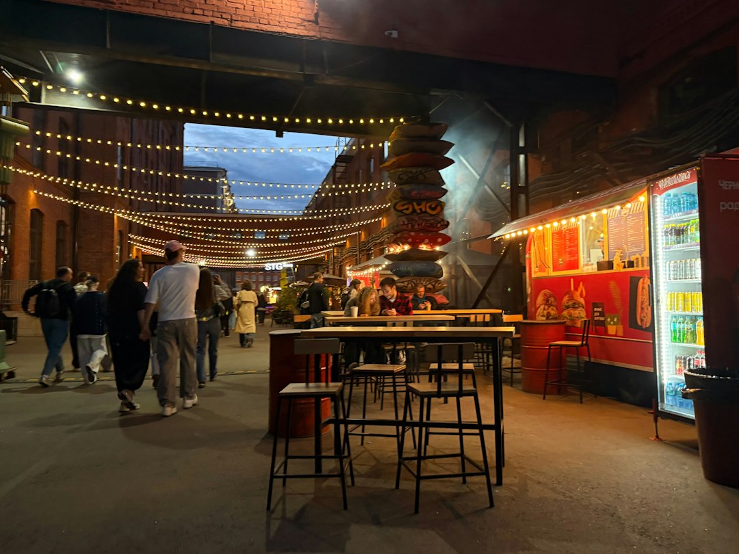 outdoor food truck park at night with string lights and people eating