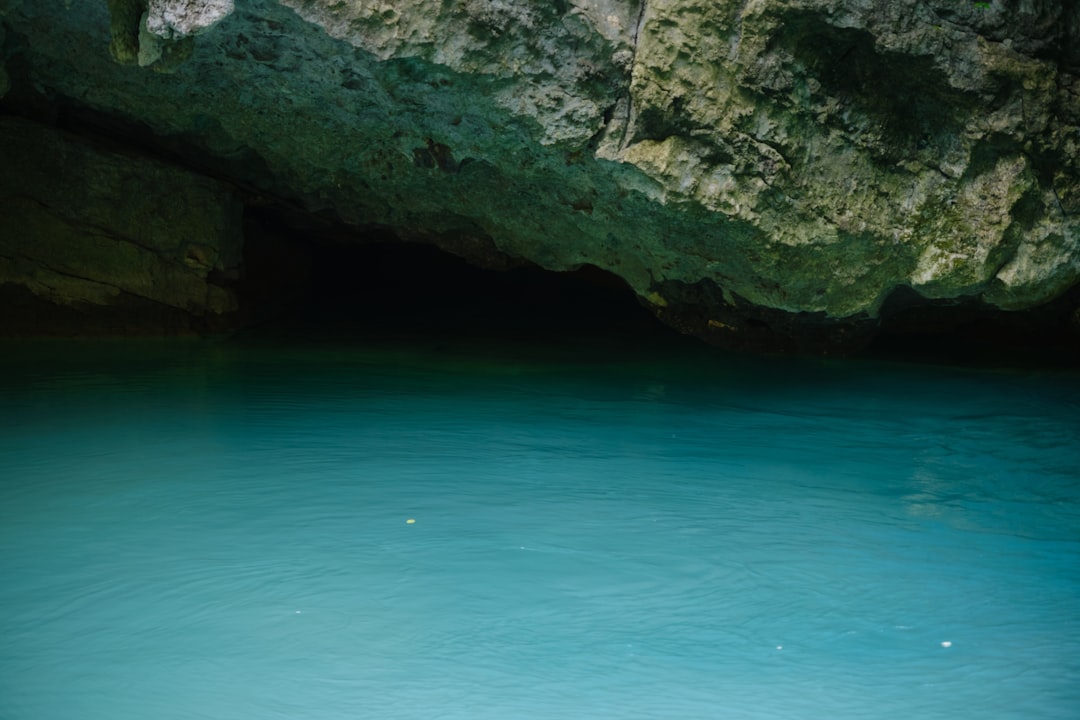 underwater view of sunlight rays piercing through a cave opening into blue water
