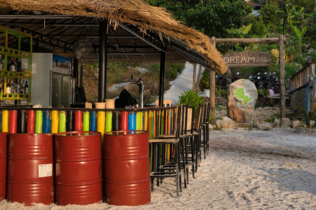 a rustic beach restaurant exterior with colorful signs and sand
