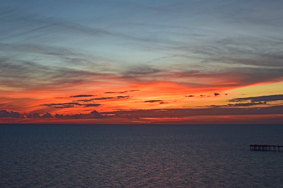 a vibrant sunset over the long wooden fishing pier at Pier Park in Panama City Beach