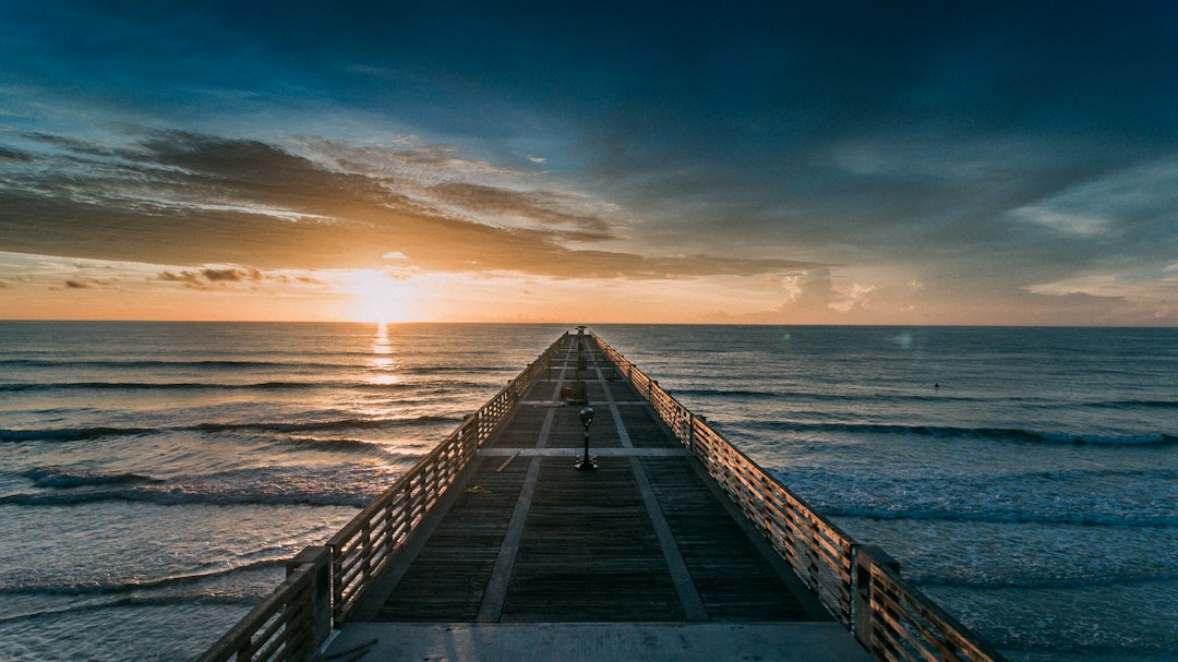 long wooden fishing pier stretching into the ocean at sunrise