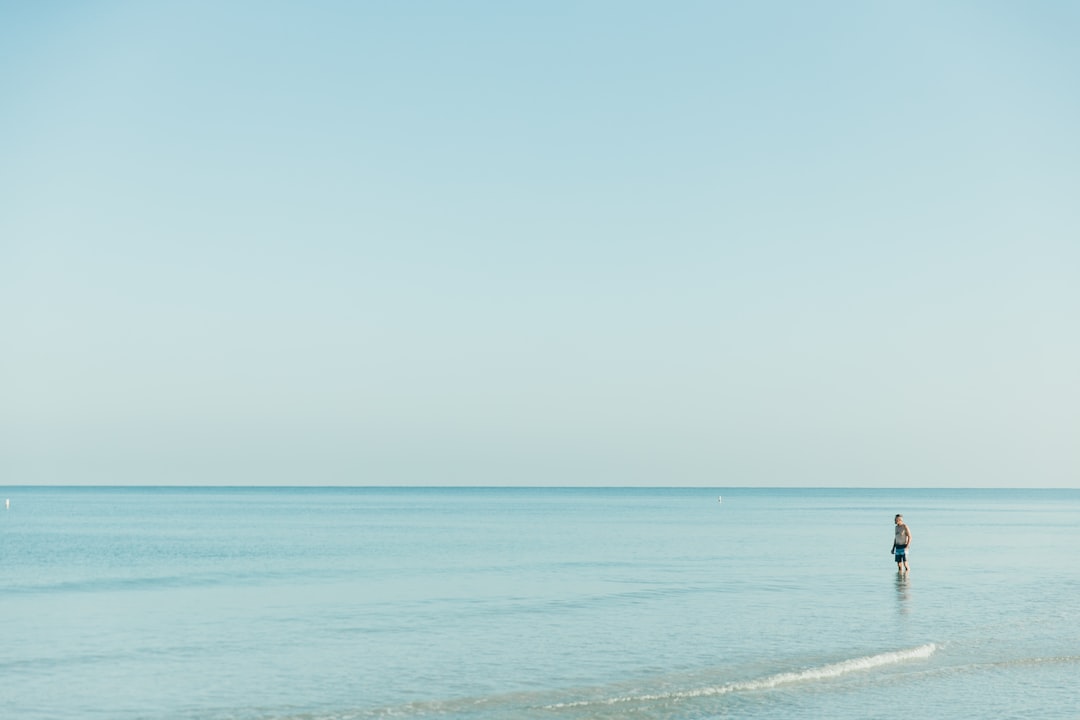 person paddleboarding on calm turquoise water near a beach in Florida