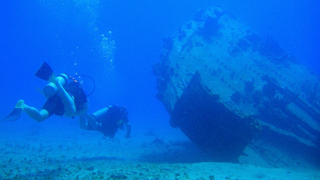 scuba diver exploring a sunken shipwreck in clear blue water