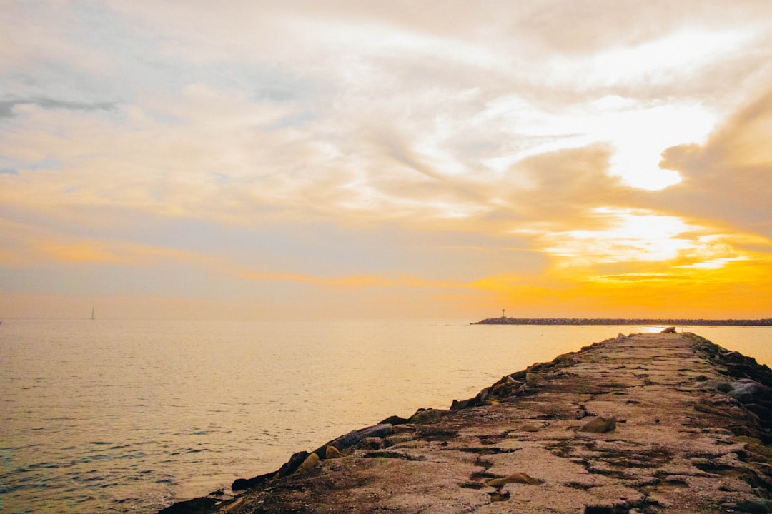 stone jetty at sunset with emerald green ocean water