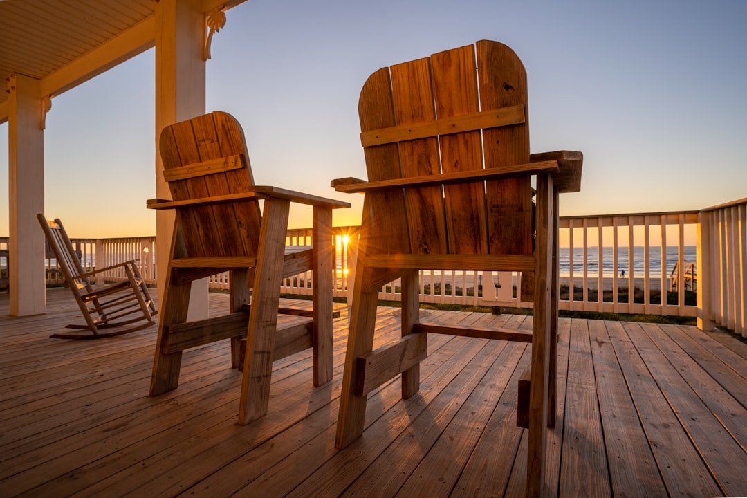couple relaxing on a beach porch in adirondack chairs at sunset