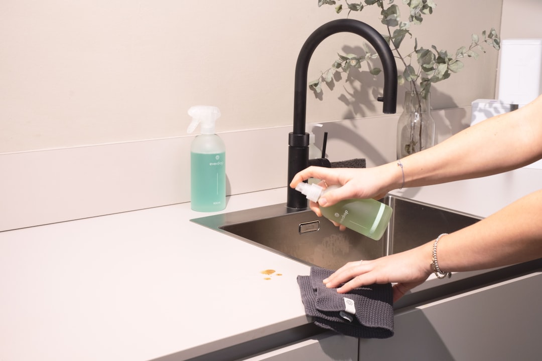 professional cleaner in uniform wiping down a granite kitchen countertop in a modern vacation rental