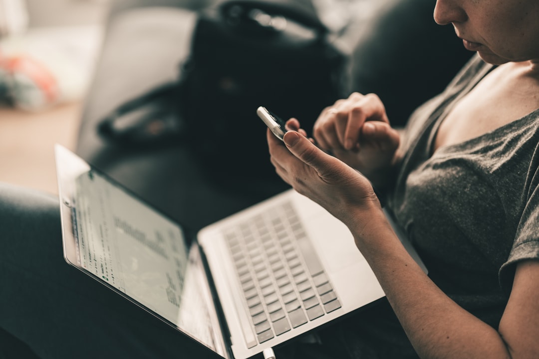 stressed person looking at a laptop and phone simultaneously