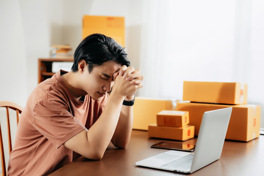 stressed person on a laptop surrounded by cleaning supplies