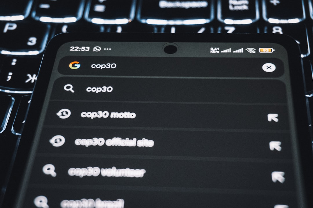 close-up of a person typing a search into a Google search bar on a laptop