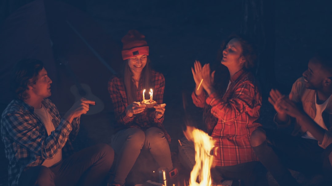 diverse group of friends laughing around a campfire at night