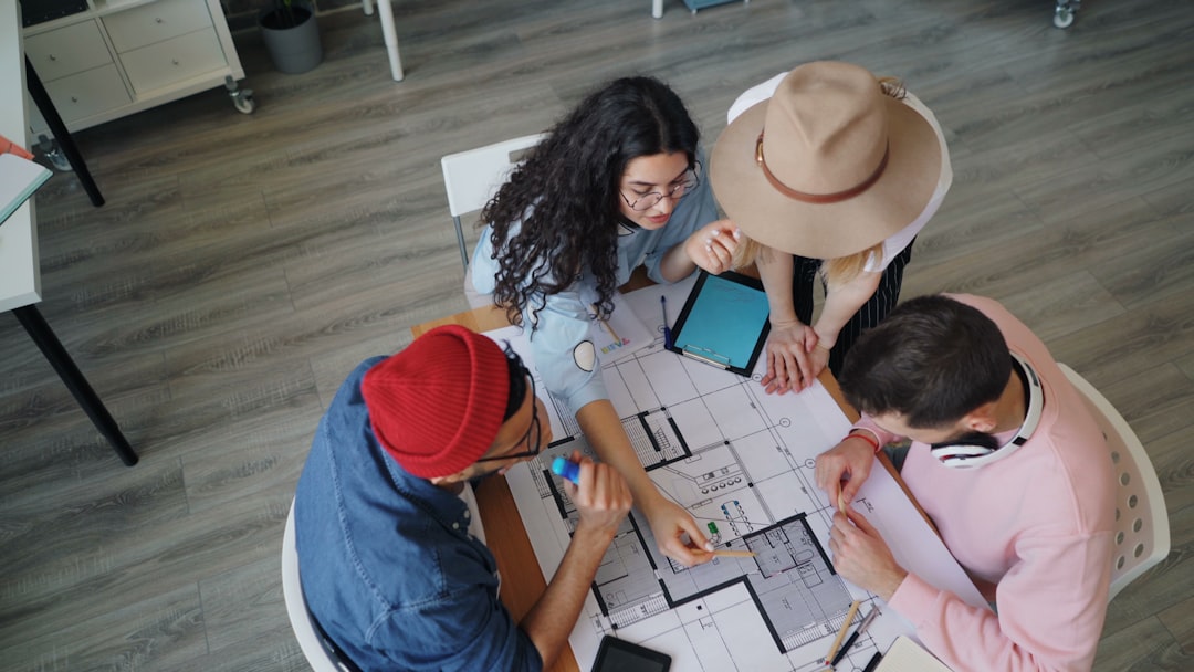 diverse group of friends planning a trip around a table with laptops and maps